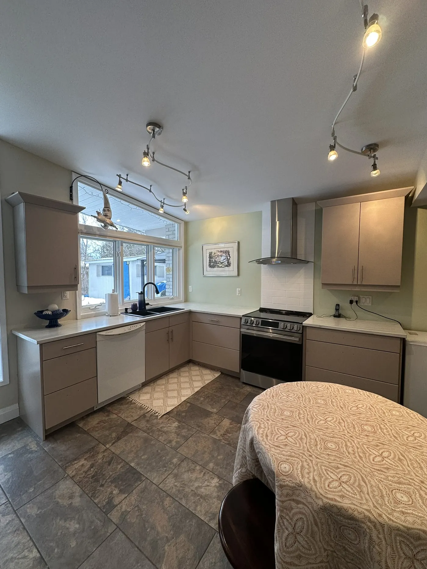 Cream-painted kitchen cabinets after a budget brush-and-roll repaint by All In One Painting in North Bay